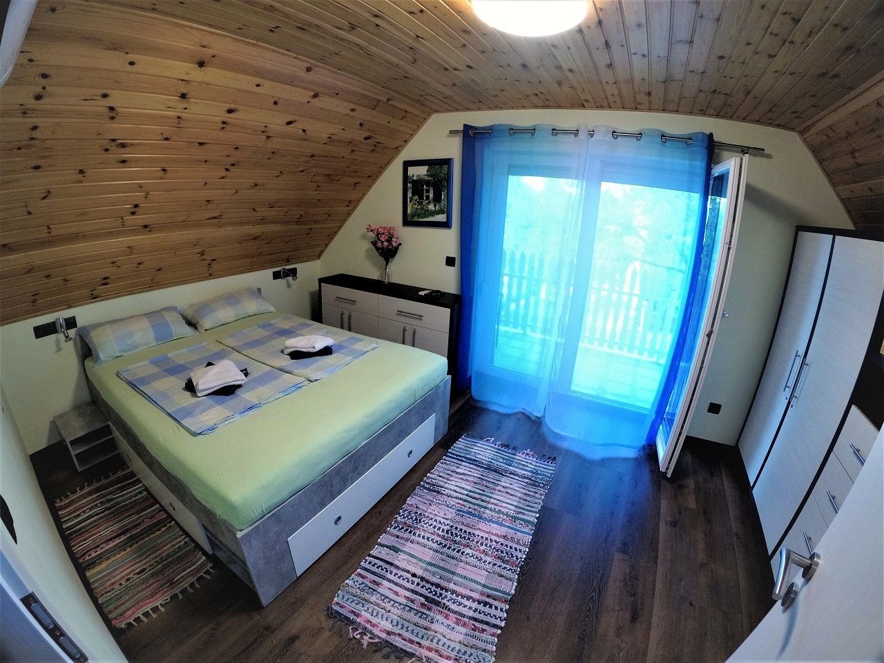 Das Schlafzimmer mit Balkon, Doppelbett und Holzdecke