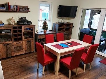 The dining table with red chairs, next to the terrace door